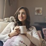 Woman relaxing with a cup of coffee on a sofa in a cozy living room.