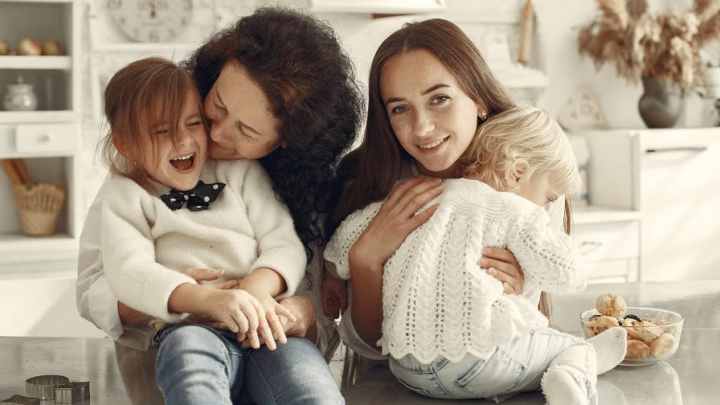 A joyful family gathering in a cozy kitchen with three generations bonded in happiness.