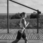 A woman jogs along a coastal boardwalk in Castelldefels, Spain, promoting fitness and outdoor exercise.